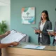 Recepcionista de clínica médica entrega documentos fiscais organizados a dois fiscais uniformizados